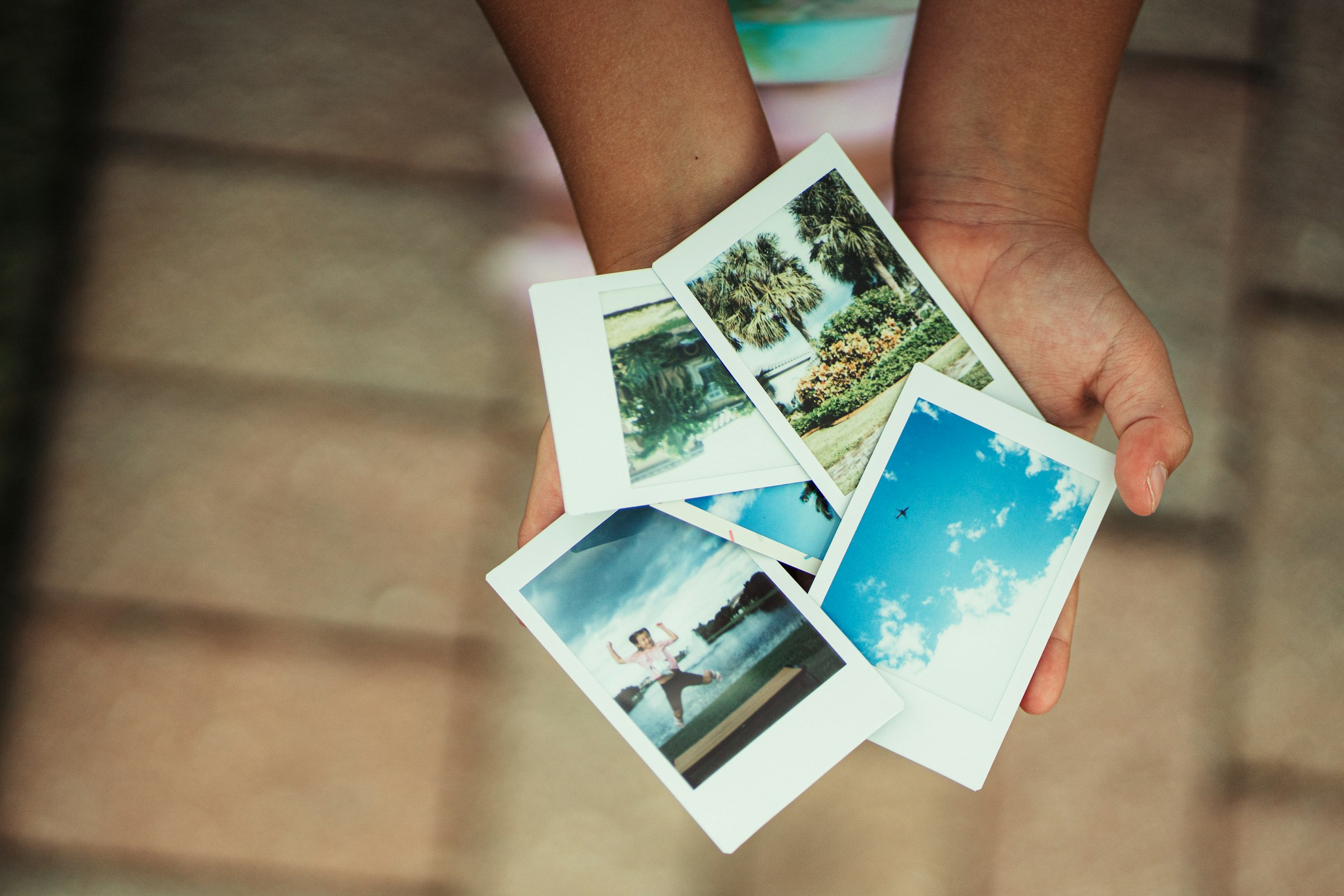 Ruke drže četiri otisnute polaroid fotografije s ljetnim motivima